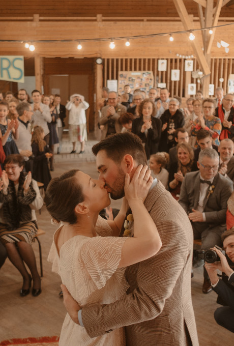 mariés qui s'embrassent dans la halle avec les invités cérémonie laïques mariage hiver